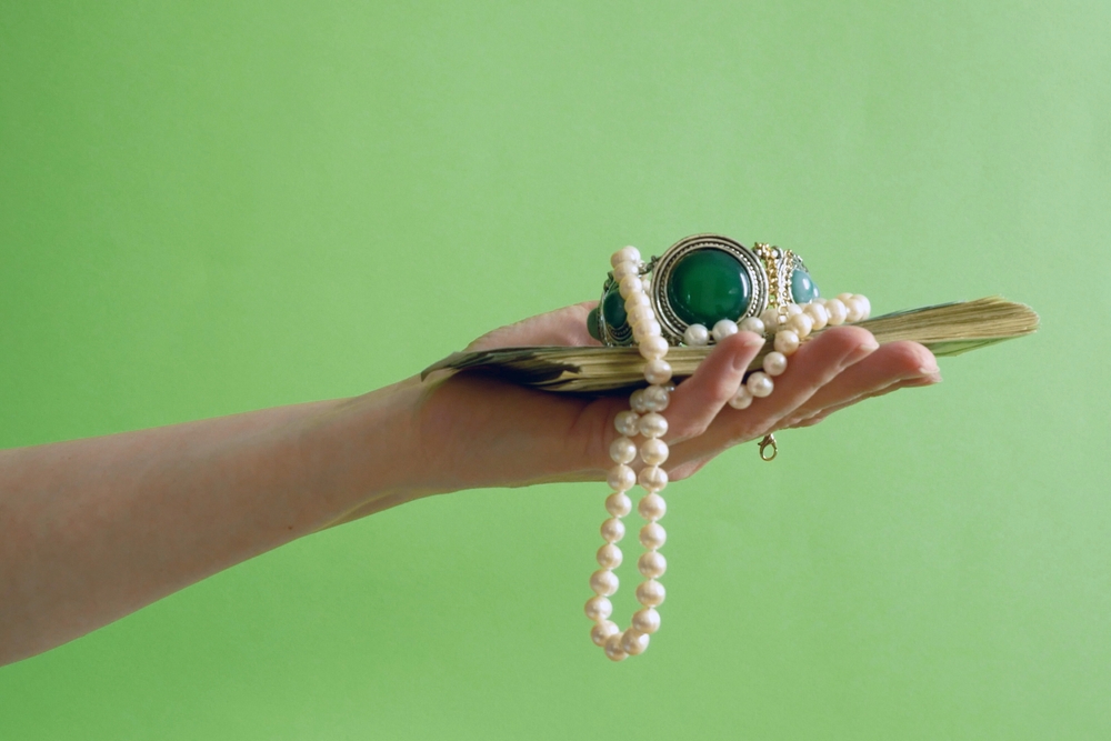 Hand,holding,vintage,silver,bracelet,with,green,stones,,pearls,necklace